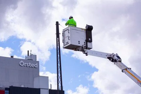 Lineworker working on power lines in crane bucket high in the air Stock Photos