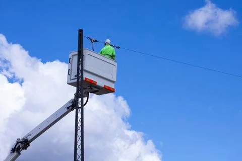Lineworker working on power lines in crane bucket in the air from lift Foto stock