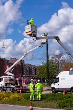 Lineworkers working on power lines in crane buckets high in the air Stock Photos