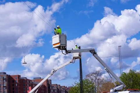 Lineworkers working on power lines in crane buckets high in the air Foto stock