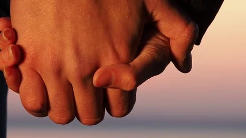 Linked hands of a guy and a girl in sunset rays 2 Stock Footage