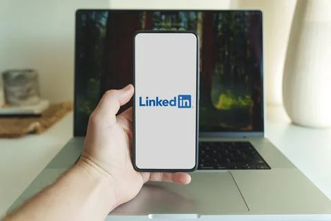 Linkedin application logo on smartphone screen in front of laptop Stock Photos