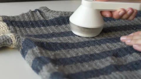 Lint remover cleaning blue wool sweater fabric to extend garment life and reduce Stock Footage 331010354