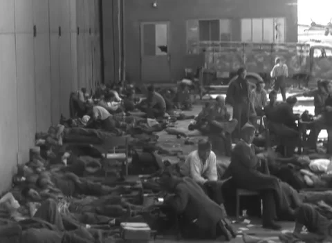 LINZ, AUSTRIA - 1945: Folding cots on concrete - men fill an open-ended hangar Stock Footage 344600145