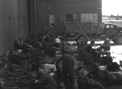 LINZ, AUSTRIA - 1945: Trestle table work - men rest along a hangar wall Stock Footage 344600134