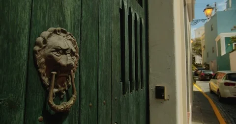 Lion head door knocker in the foreground with cars driving on a narrow street in Stock Footage 125112829