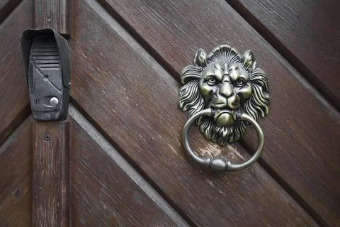 Lion knocker and intercom on an old wooden door . Stock Photos