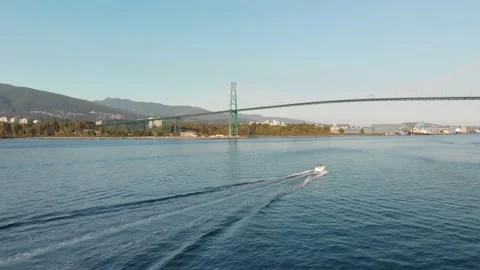 Lions Gate Bridge in Vancouver's harbor with pleasure craft passing by next to Stock Footage 142616202