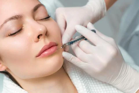 Lip augmentation and correction procedure in a cosmetology salon. The specialist Stock Photos