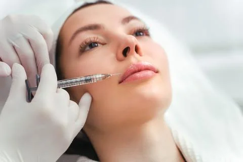 Lip augmentation and correction procedure in a cosmetology salon. The specialist Stock Photos