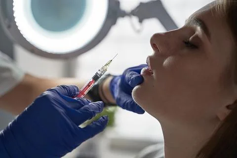 Lip augmentation and correction procedure in a cosmetology salon. The specialist Stock Photos