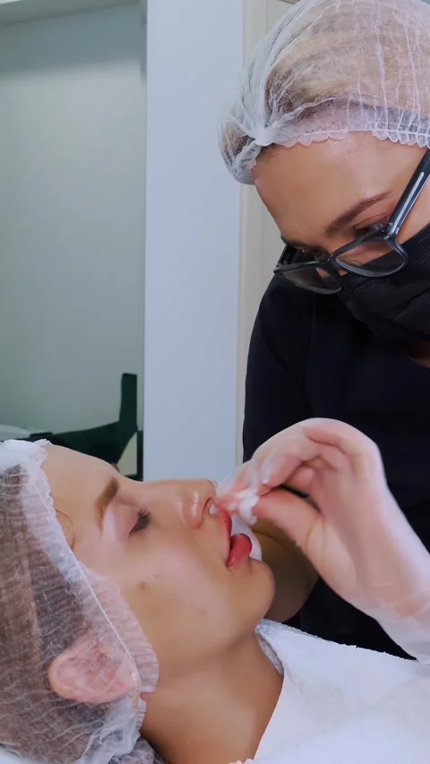 Lip augmentation procedure. Surgeon, in medical mask and gloves, kneads and Stock Footage 314656230