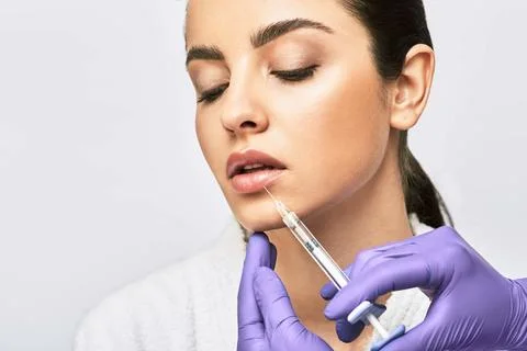 Lip augmentation procedure. Syringe with lips filler near beautiful woman's m Fotos Stock