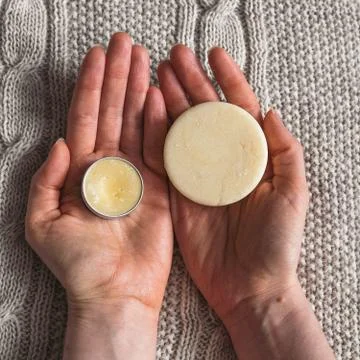 Lip balm and solid shampoo in female hands Stock Photos