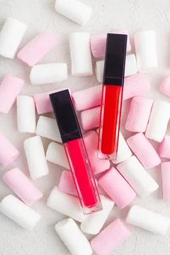 Lip gloss and marshmallows. Candy and glitter. The concept of cosmetics without Stock Photos