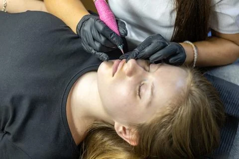 Lip permanent makeup application in a professional beauty studio with a focused Stock Photos