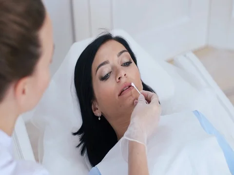 Lip permanent makeup procedure in salon. Doctor puts on the lip anesthesia cream Stock Footage 74522872