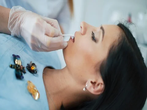 Lip permanent makeup procedure in salon. Doctor puts on the lip anesthesia cream Stock Footage 74523186