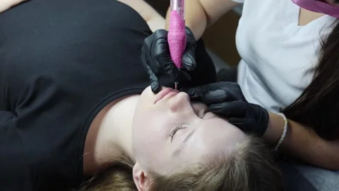Lip tattooing procedure using machine, pigment being applied Stock Footage 316430498