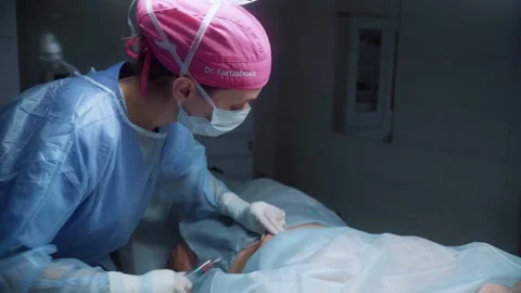 Liposuction procedure in a modern operating room with skilled surgeon performing Stock Footage 295864989