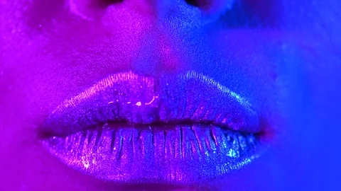 Lips kiss in bright neon UV lights. Beauty sexy model lips close-up Stock Footage