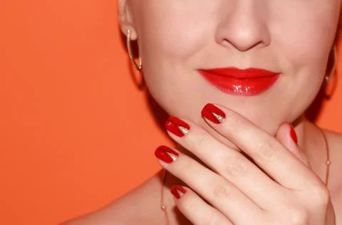 Lips with red lipstick and red manicure on an orange background. Classic lips Stock Photos