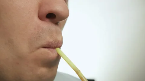 Lips of a young man drinking through a cocktail tube, close-up, light background Stock Footage 147924380