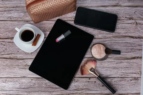 Lipstick on tablet surrounded by coffee cup, makeup bag, smartphone, pressing Stock Photos