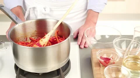 Liquid and a bay leaf being added to a pepper medley in a pan Stock Footage 24657845