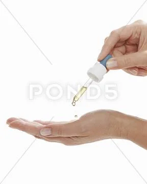 Liquid being dripped onto the palm of the hand with a pipette Stock Photos