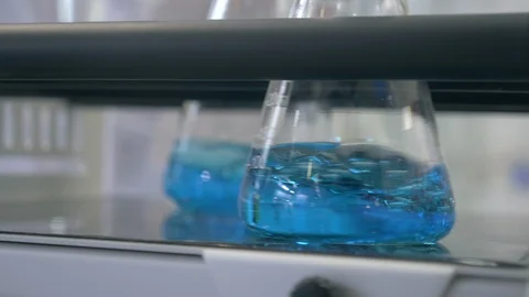 Liquid being mixed in laboratory glassware. mixing blue liquid in laboratory Stock Footage 112000390