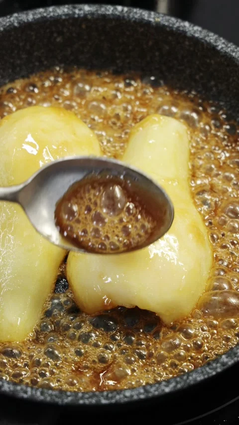 Liquid caramel pours over pear pieces in frying pan. Video stock 344769727