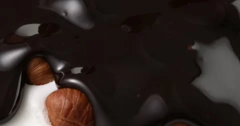 Liquid chocolate on cream with nuts. chocolate flow covers hazelnuts and cream. Stock Footage 242490186