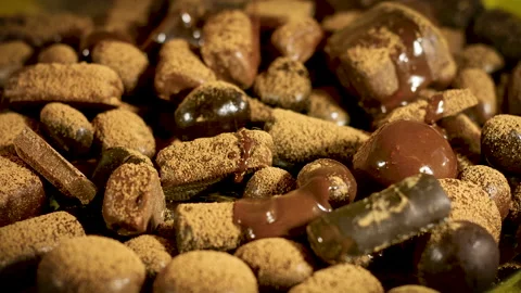 Liquid chocolate flows on assorted chocolates sprinkled with grated cocoa Stock Footage 131624043