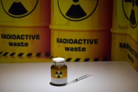 Liquid container and syringe on the background of barrels of radioactive wast Foto stock