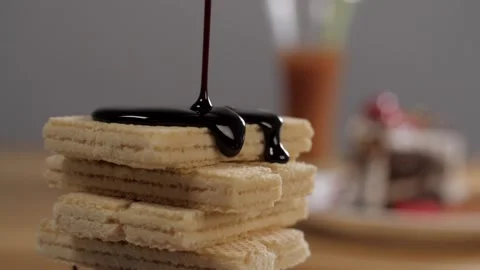 Liquid dark chocolate pouring on white thin biscuit waffles stacked together Stock Footage 153199767
