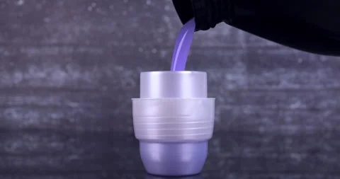 Liquid detergent flowing from the bottle into the container Stock Footage 297887057