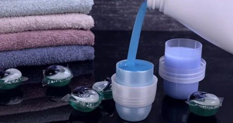 Liquid detergent flowing into the container in front of the towels Stock Footage 297887041