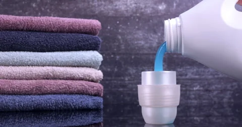 Liquid detergent flowing into the container in front of the towels Stock Footage 297887066
