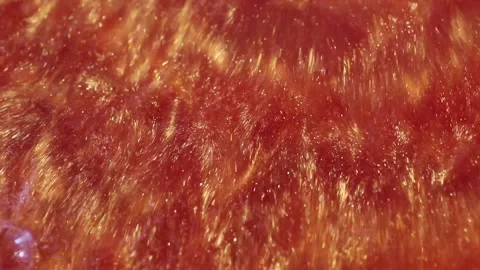 Liquid with dissolved particles of orange candurin is bubbling and mixing vigoro Stock Footage 306073752