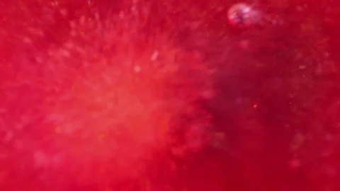 Liquid with dissolved particles of red candurin is bubbling and mixing vigorousl Stock Footage 306073809