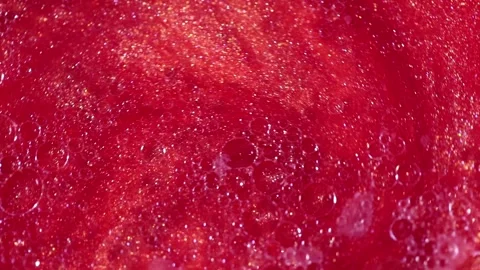 Liquid with dissolved particles of red candurin and bubbles slowly moves and shi Stock Footage 306073878