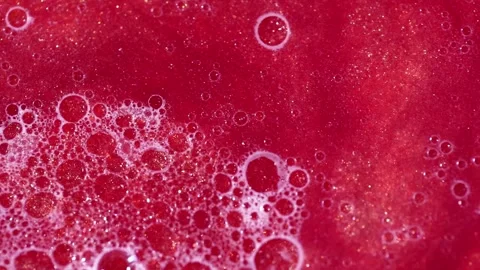 Liquid with dissolved particles of red candurin and bubbles slowly moves and shi Stock Footage 306073890