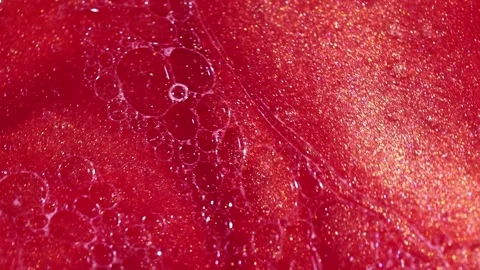 Liquid with dissolved particles of red candurin and bubbles slowly moves and shi Stock Footage 306073926