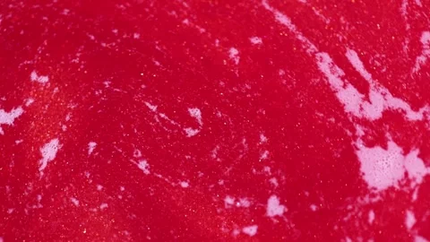 Liquid with dissolved particles of red candurin and bubbles slowly moves and shi Stock Footage 306074011