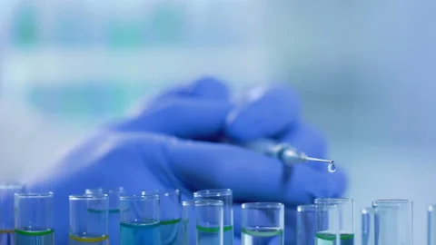 Liquid dripping from syringe into test tubes, drug development in laboratory Stock Footage
