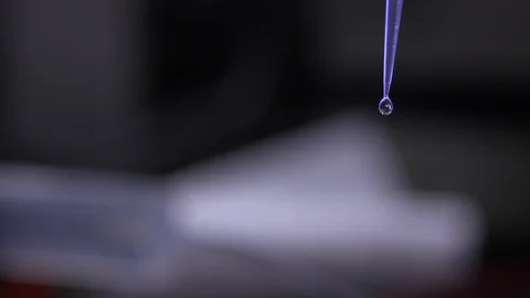 Liquid drop falling from a chemical dropper Stock Footage 93522628