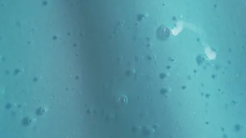 Liquid drops of blue paint cosmetics product flowing on the blue surface. M.. Stock Footage 249733950