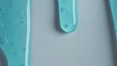 Liquid drops of blue paint cosmetics product flowing on the blue surface. M.. Stock Footage 249733994