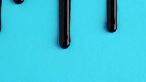 Liquid drops of bright black paint color flowing on the blue surface. Macro.. Stock Footage 250163640